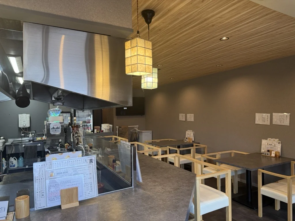 木のテーブルとカウンター席が見える飲食店の店内風景